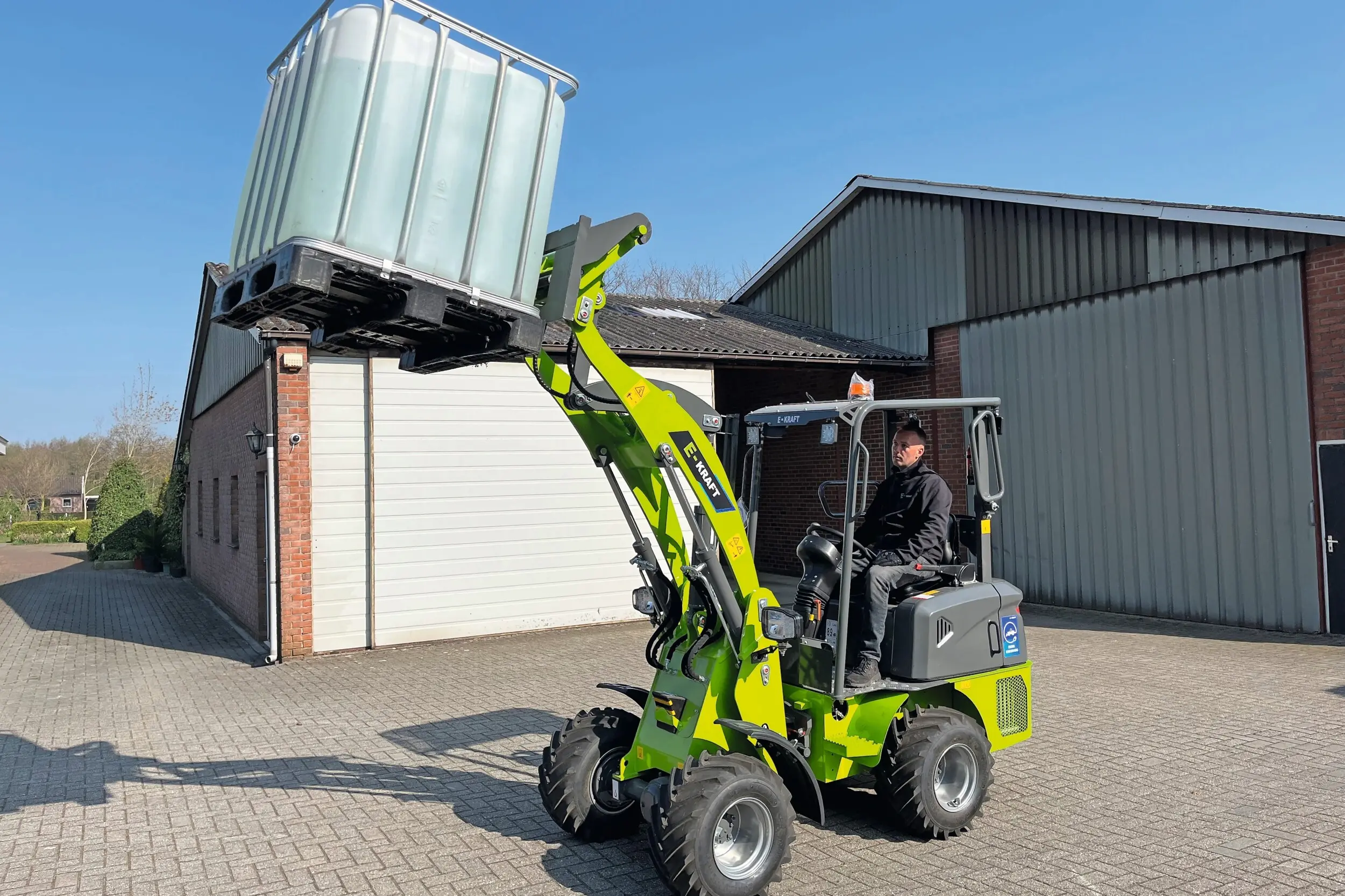 De E-Kraft E-1000 valt op met zijn felle kleuren. Het hefvermogen van de E-1000 is volgens de papieren 1.000 kilo en dat blijkt ook in de praktijk. De minishovel tilt vrij gemakkelijk een vat met water op. Foto’s: Lars Verhage